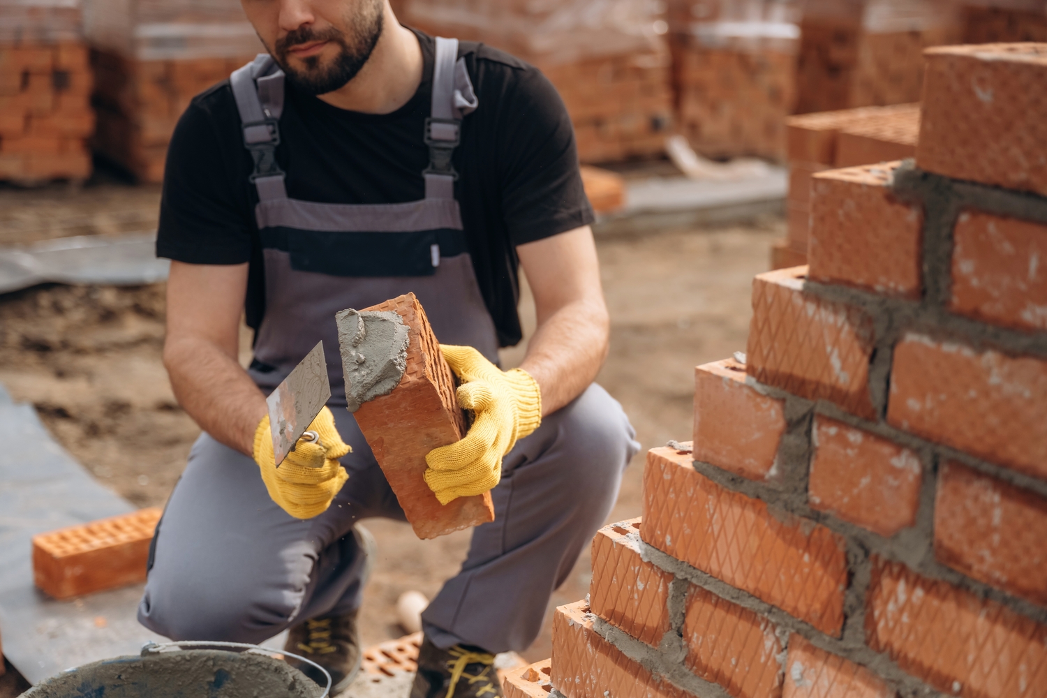 Busy by working with bricks. Construction worker is at job outdoors.