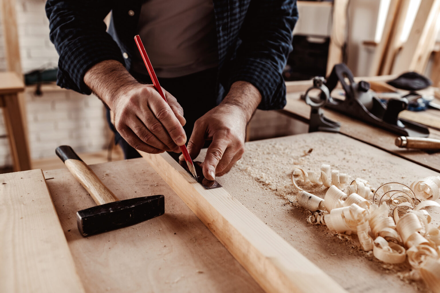 Carpenter makes pencil marks on a wood plank close up