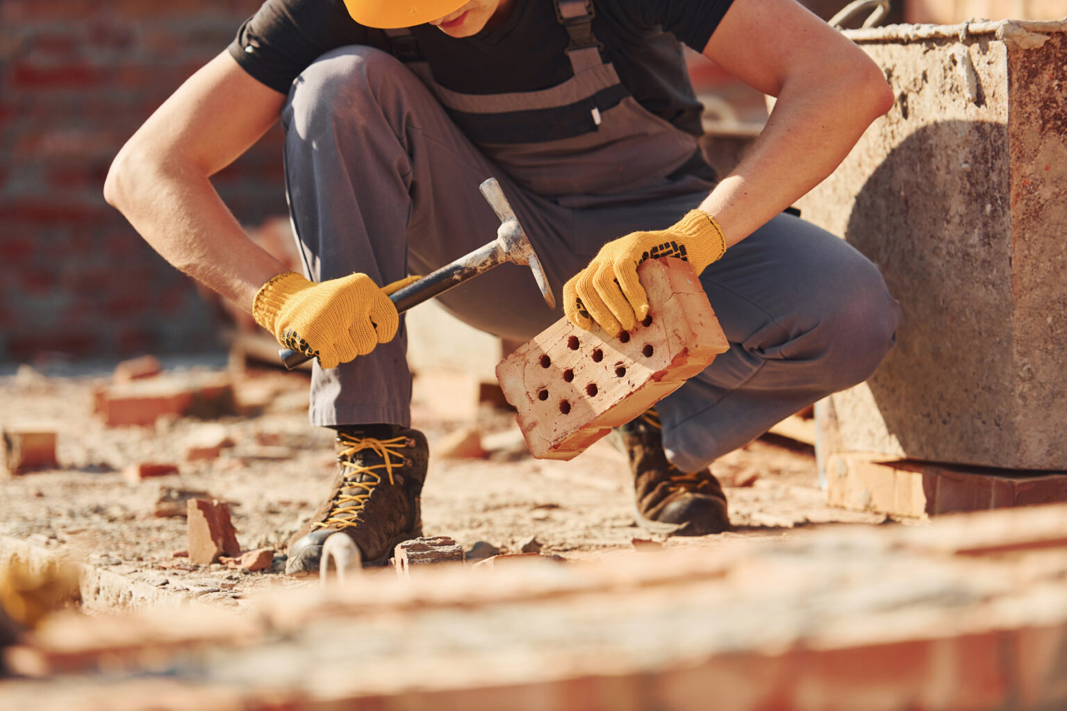 Construction worker in uniform and safety equipment sits and have job on building.