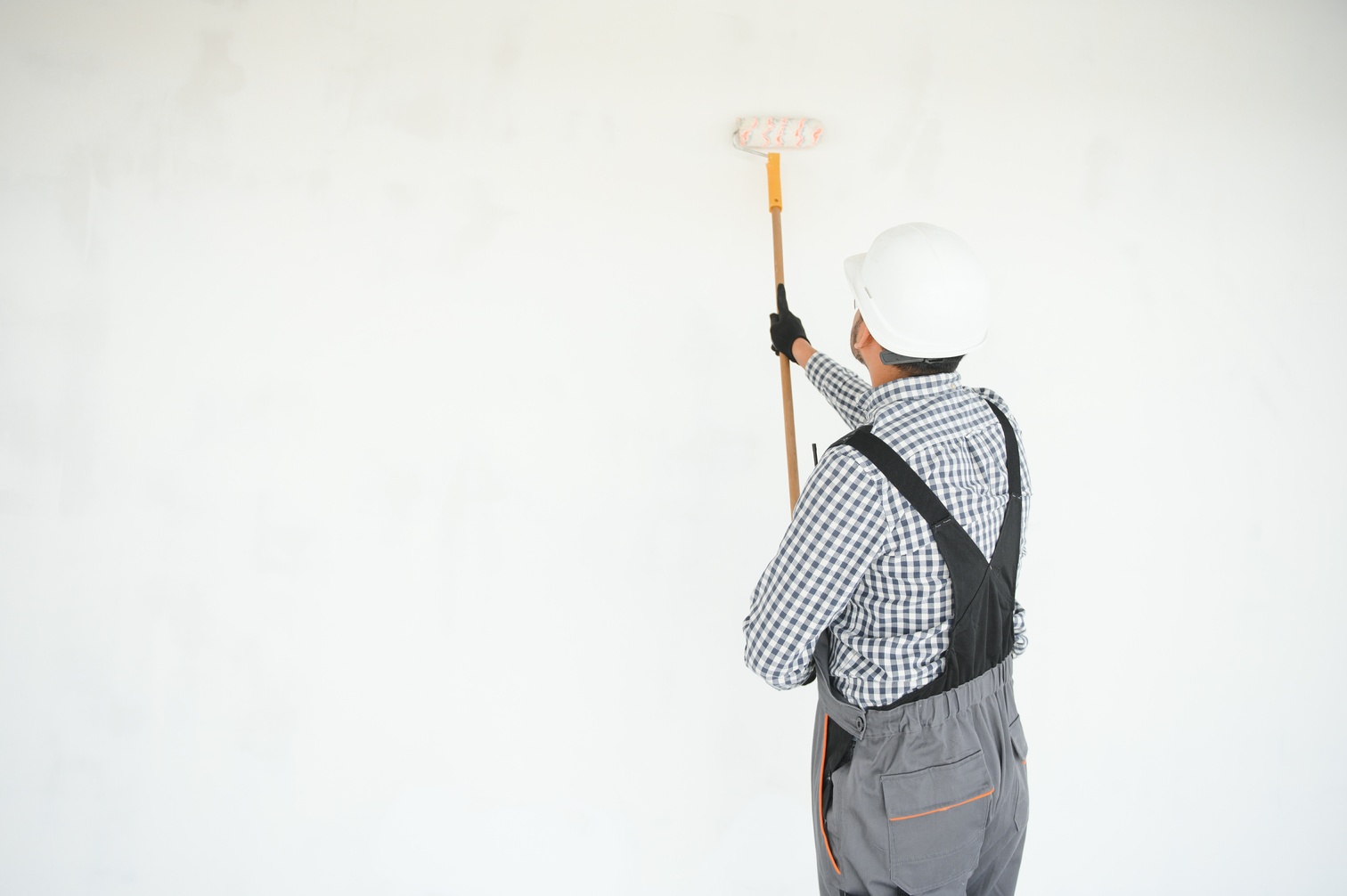 Indian Painter painting the office wall with roller paint.